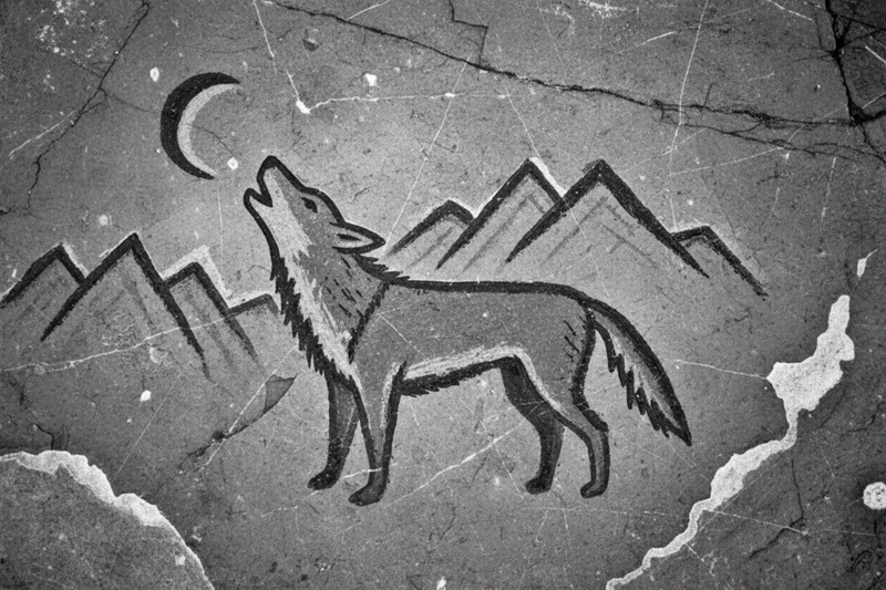 A grayscale caveman drawing of a wolf howling